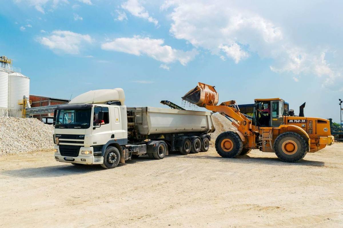 A loader filling a tipper lorry at an aggregates yard
